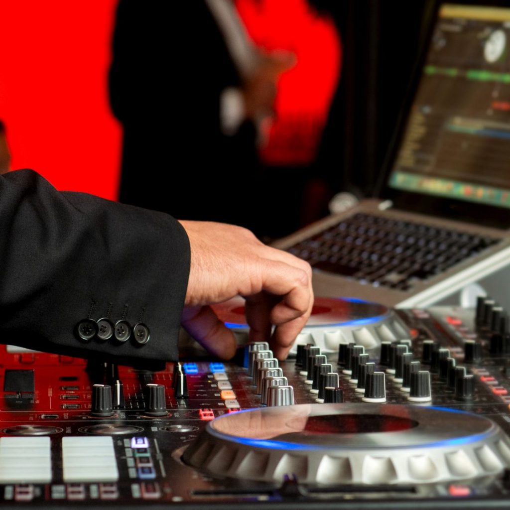 Disc jockey in elegant suit mixes music at party, close up